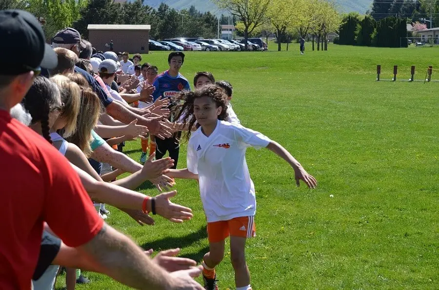 team of children showing good sportsmanship by high fiving the fans