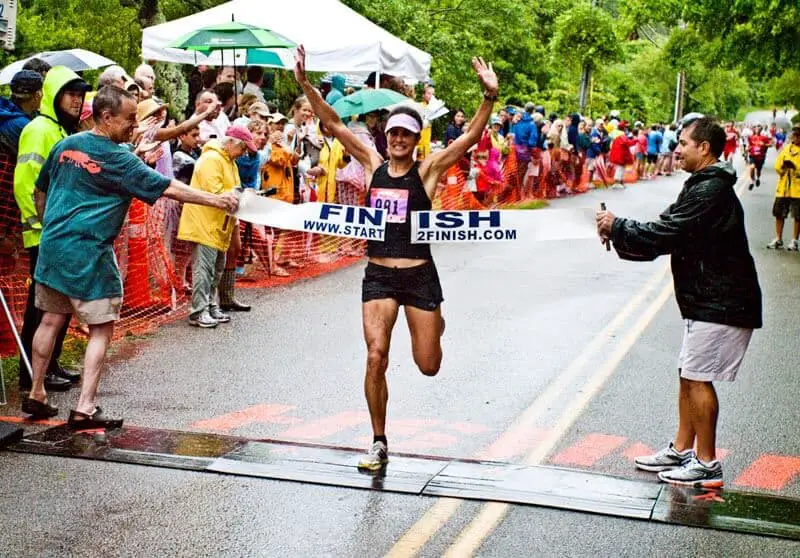 woman crossing the finish line and smiling