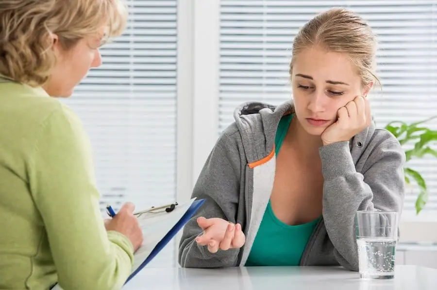 girl looking sad and talking to a therapist