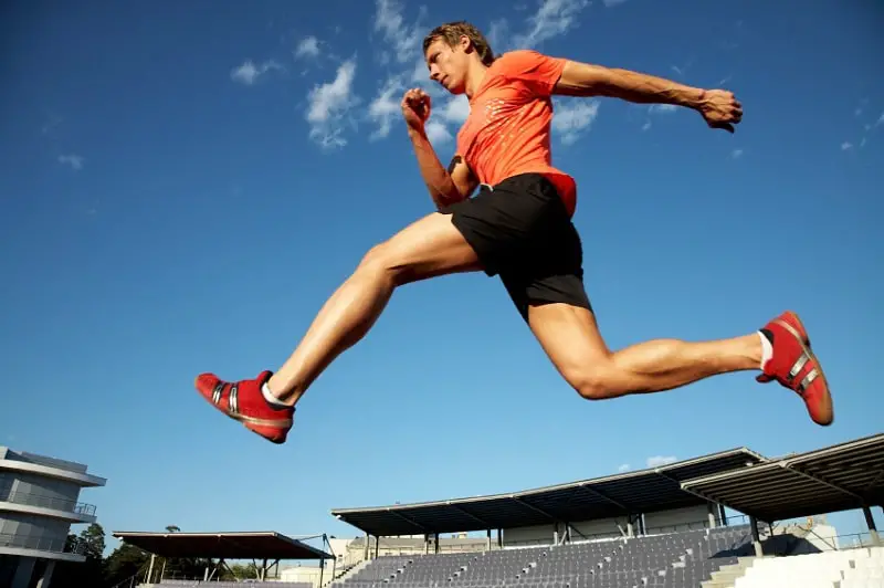 athlete jumping over hurdles