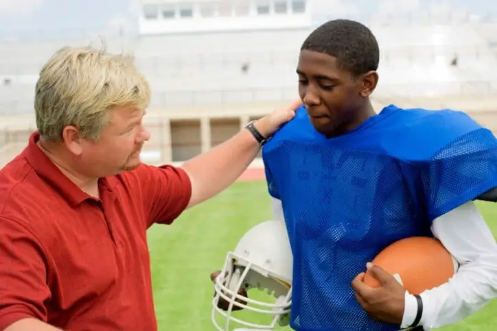 middle aged coach talking to a young American football player