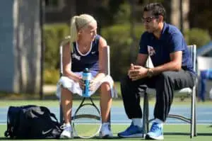male tennis coach and female tennis player talking