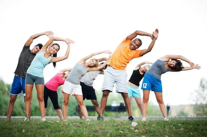 group of men and women stretching in the park